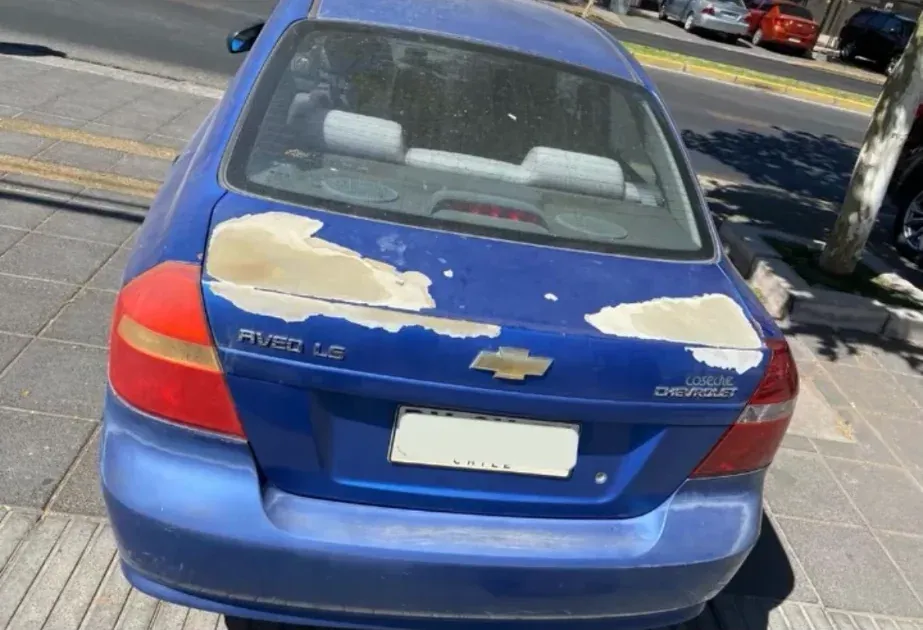 Antes: Chevrolet Aveo azul con la pintura del portón trasero desprendida