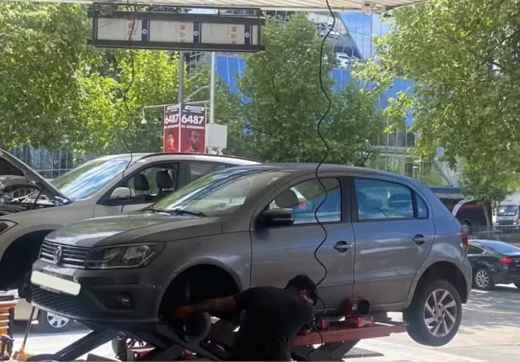Volkswagen sobre un elevador mientras un técnico trabaja en la rueda delantera