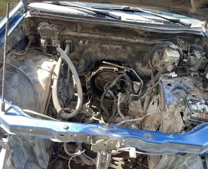 Compartimento del motor de una camioneta azul, con la transmisión a la vista